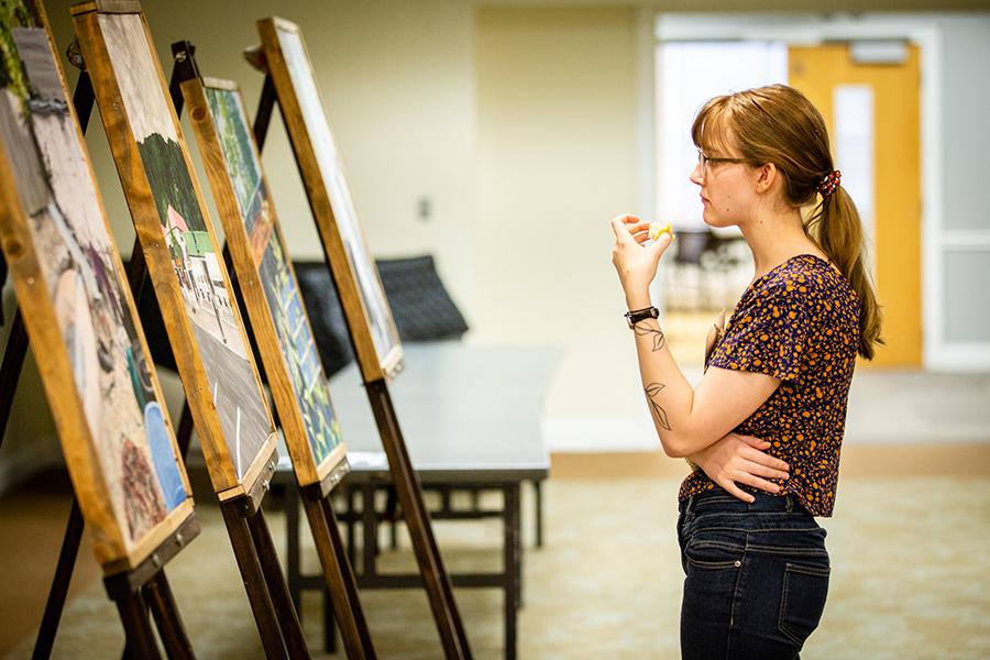 A student takes in a series of paintings during last year's Celebration of Quality academic symposium. Students are invited to submit their academic work for presentation at the 2020 Celebration of Quality, which takes place April 17. (Photo by Brandon Bland/Northwest Missouri State University)